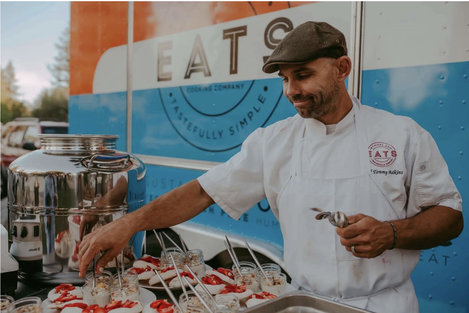 Chef Tommy plating dishes in front of the EATS food truck